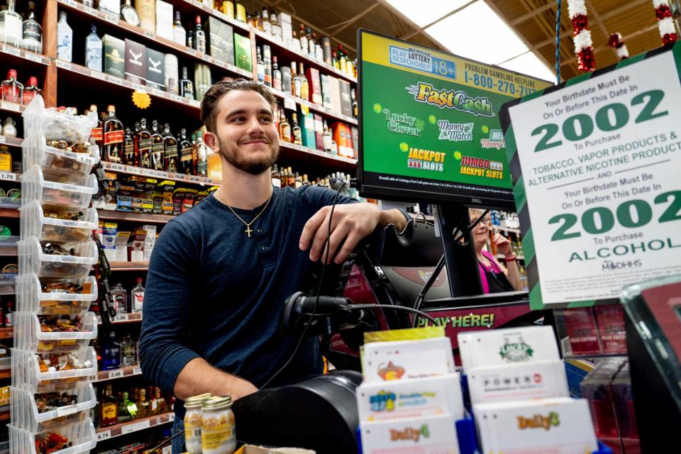 Food Castle manager Jacob Nannoshi stands at the lotto machine that printed the winning $842.4 million Powerball jackpot at his family's business in Grand Blanc Township on Tuesday, Jan. 2, 2023.
