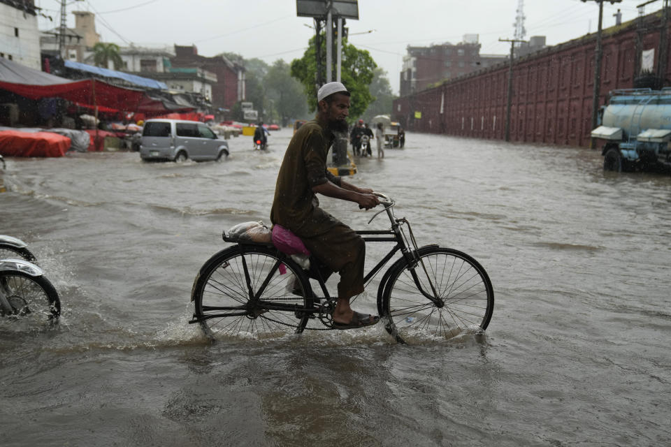 A cyclist rides through a flooded road caused by heavy monsoon rainfall in Lahore, Pakistan, Wednesday, July 5, 2023. Officials say heavy monsoon rains have lashed across Pakistan, killing a number of people. (AP Photo/K.M. Chaudary)