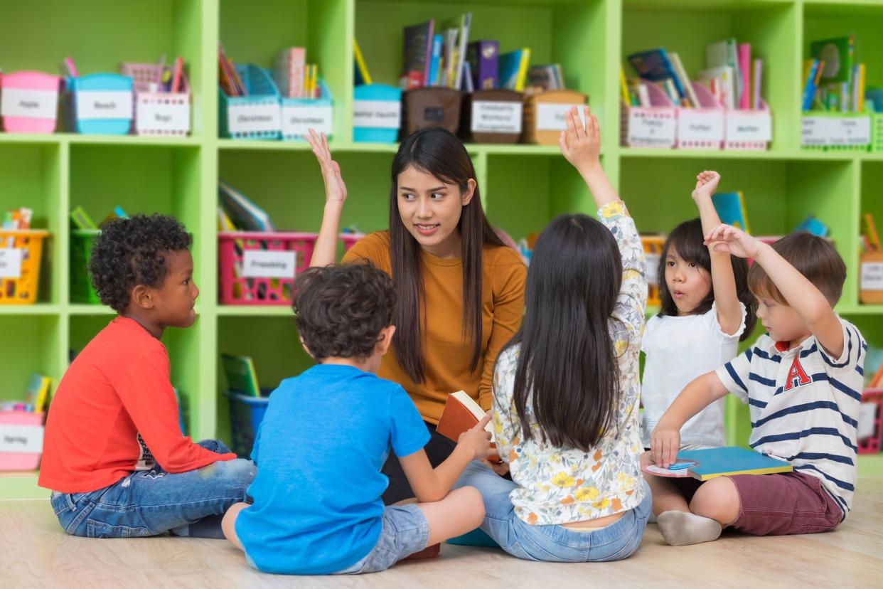 students and teacher sitting near green cubbies in colorful classroom