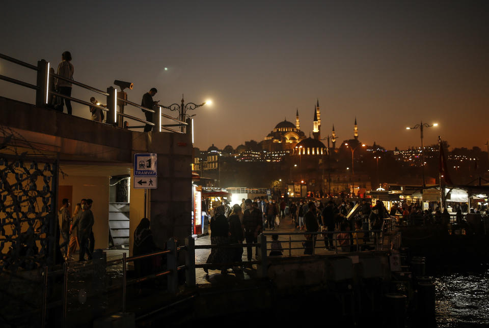 Backdropped by the Suleymaniye Mosque people stroll along the banks of the Bosporous in Istanbul, Turkey Friday, Oct. 23, 2020. In much of Europe, city squares and streets, be they wide, elegant boulevards like in Paris or cobblestoned alleys in Rome, serve as animated evening extensions of drawing rooms and living rooms. As Coronavirus restrictions once again put limitations on how we live and socialize, AP photographers across Europe delivered a snapshot of how Friday evening, the gateway to the weekend, looks and feels. (AP Photo/Emrah Gurel)