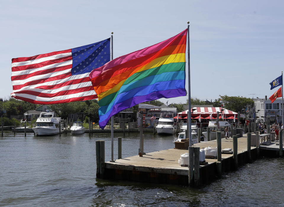 In this June 23, 2013 photo, an American flag and a LGBT Rainbow flag are displayed on the ferry dock in the Fire Island community of Cherry Grove, N.Y. The 1969 Stonewall uprising in New York City is generally accepted as the Lexington and Concord of the gay rights revolution - the first shots in a battle that eventually led to last week's landmark Supreme Court decision legalizing gay marriage. But in this seaside resort 60 miles east of Manhattan, reports that homosexuals were standing up for their rights that summer of Woodstock and moon landings was hardly breaking news: a gay community in Cherry Grove had been thriving there for at least two decades before Stonewall. (AP Photo/Seth Wenig)