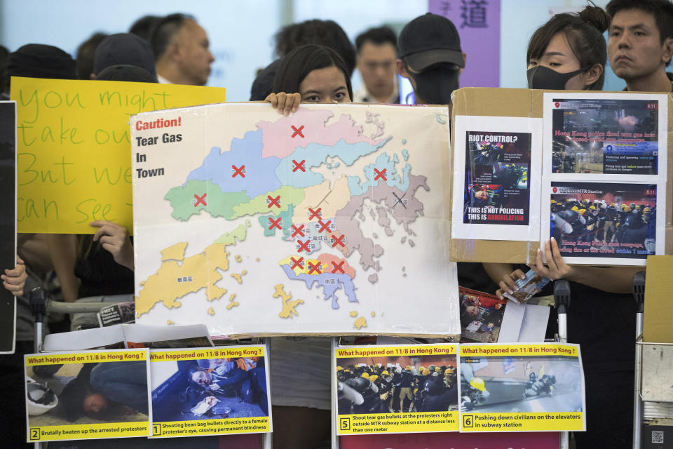 Protesters show posters to travelers at the arrival hall of the Hong Kong International Airport in Hong Kong, Tuesday, Aug. 13, 2019. (Photo: Vincent Thian/AP)