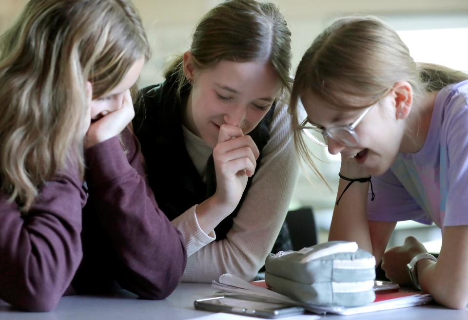 Greenville Middle School students Tabitha DeGroot, left, Alaina Hunter, center, and Annabelle Todd watch a video they created for their math class on a cellphone.