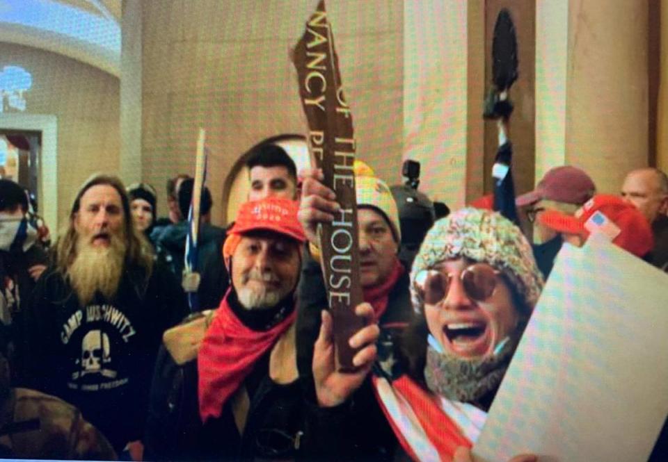 William Merry (red cap), Paul Westover (yellow stocking cap, behind sign) and Emily Hernandez (wearing sunglasses) during the U.S. Capitol invasion on Jan. 6, 2021.