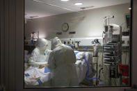 In this photo taken on Friday, March 27, 2020, healthcare workers assist a patience at one of the intensive care units (ICU) at German Trias i Pujol hospital in Badalona, in the Barcelona province, Spain. The new coronavirus causes mild or moderate symptoms for most people, but for some, especially older adults and people with existing health problems, it can cause more severe illness or death. (AP Photo/Anna Surinyach)