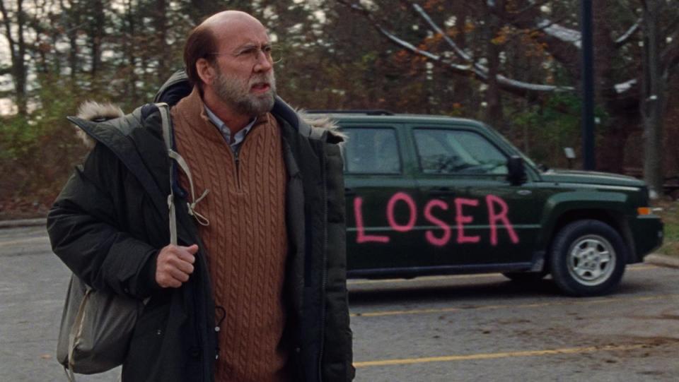 Nicolas Cage angrily stands next to his car on which people have painted "Loser" in Dream Scenario.