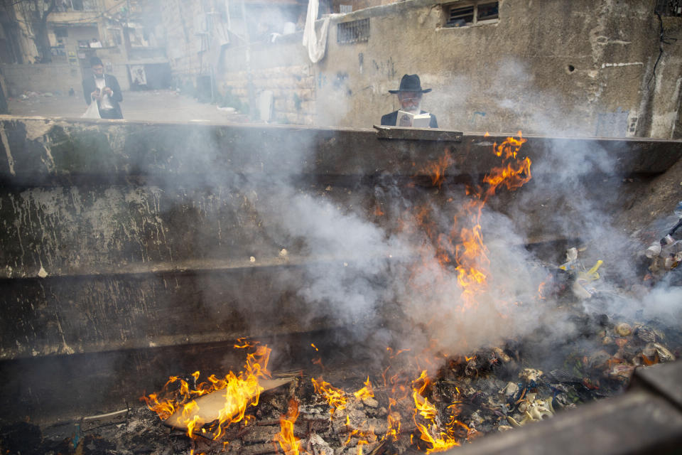 An ultra-Orthodox Jewish men pray as they burn leavened items in final preparation for the Passover holiday in the Orthodox neighborhood of Mea Shearim in Jerusalem, Wednesday, April 8, 2020. Israeli Prime Minister Benjamin Netanyahu announced Monday a complete lockdown over the upcoming Passover holiday to control the country's coronavirus outbreak, but offered citizens some hope by saying he expects to lift widespread restrictions after the week-long festival. Passover begins on sundown Wednesday. (AP Photo/Ariel Schalit)