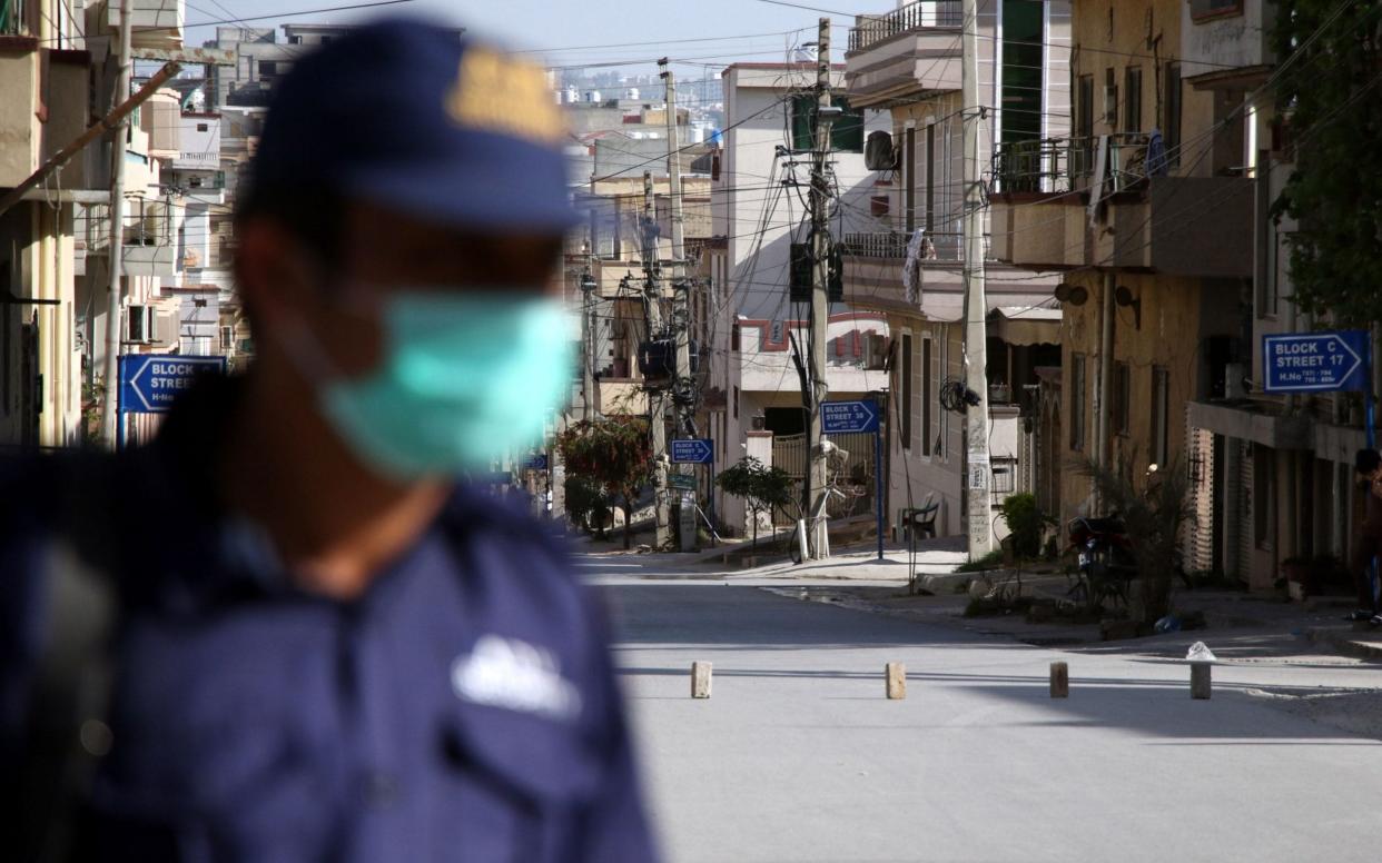 A Pakistani security official stands guard at a sealed residential area, during the smart lockdown after new cases of COVID-19 were reported across the country in Islamabad, Pakistan