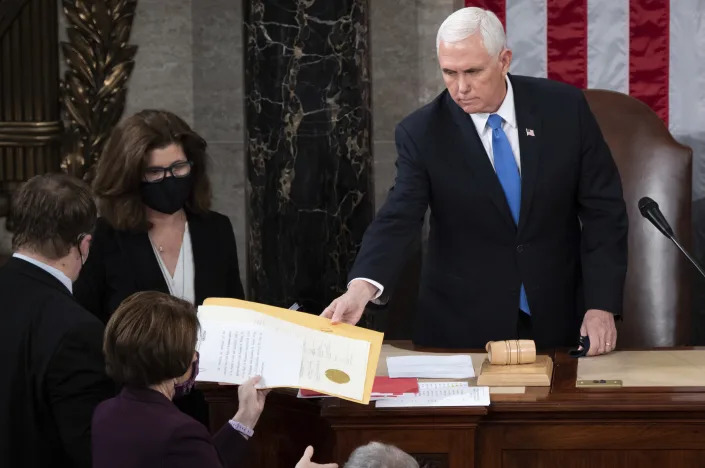 FILE - Vice President Mike Pence hands the electoral certificate from the state of Arizona to Sen. Amy Klobuchar, D-Minn., as he presides over a joint session of Congress as it convenes to count the Electoral College votes cast in November's election, at the Capitol in Washington, Wednesday, Jan. 6, 2021. Congress on Friday, Dec. 23, gave final passage to legislation changing the arcane law that governs the certification of a presidential contest, the strongest effort yet to avoid a repeat of Donald Trump's violence-inflaming push to reverse his loss in the 2020 election. (Saul Loeb/Pool via AP, File)