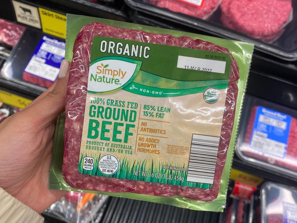 Hand holding green and clear pack of ground beef at Aldi
