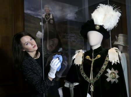 Gallery worker Caroline de Guitaut, curator at the royal collections trust, poses with part of the largest exhibition of The Queen's dresses and accessories ever shown in Scotland at the Palace of Holyroodhouse, Scotland April 20, 2016. REUTERS/Russell Cheyne