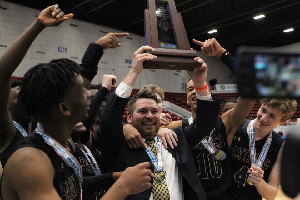 St. John Paul II boys basketball coach Titus Nixon holds the Class 3A state championship trophy after the Panthers beat Orlando Christian Prep 50-48 overtime in overtime at the RP Funding Center in Lakeland on Tuesday.
