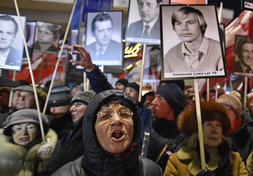 Pro-government activists hold portraits of some of the victims of the 1981 martial law and shout slogans at a passing anti-government march through the downtown on the 35th anniversary of the military crackdown by the country's former communist regime, in Warsaw, Poland, Tuesday, Dec. 13, 2016. (AP Photo/Alik Keplicz)