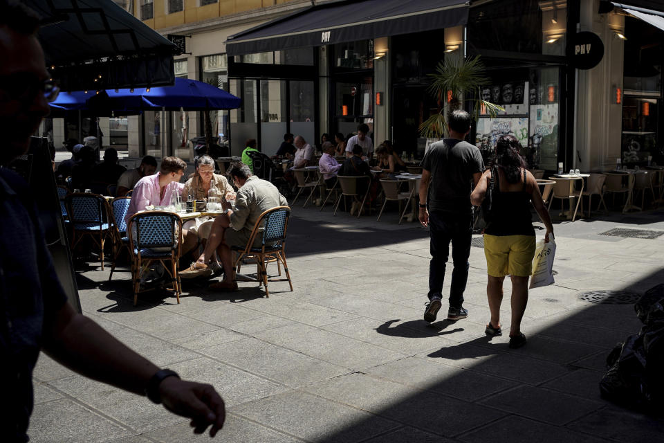 People walk on a Lyon street as others dine out, in central France, Monday, June 20, 2022. Tourism is on the rebound around the world this summer after two years of pandemic restrictions, with museums and flights packed – but the global recovery is hampered by inflation and rising virus infection rates in many regions. (AP Photo/Laurent Cipriani)