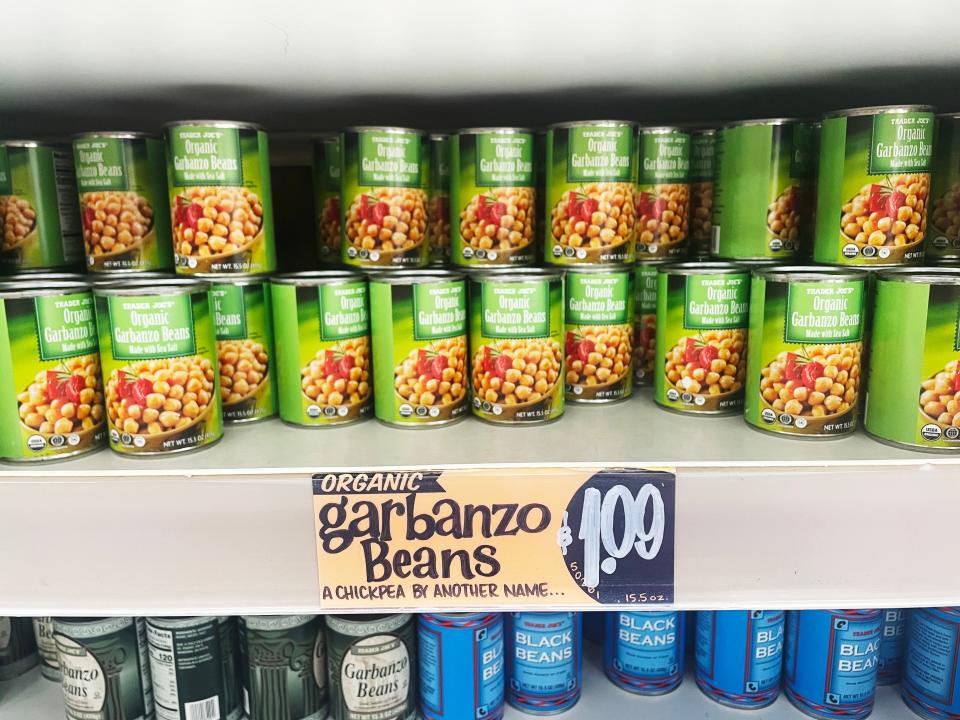 Green cans with images of garbanzo beans sit on a gray shelf at Trader Joe's I sometimes use