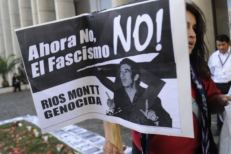 A woman holds a sign with a picture of a young Efrain Rios Montt outside court in Guatemala City on January 28, 2013. The retired general, now 86, sat stoically as Judge Miguel Galvez ordered the opening of a trial "for the crimes of genocide" and crimes against humanity