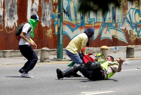 Demonstrators grab a riot police officer at a rally against Venezuela's President Nicolas Maduro's government in Caracas, Venezuela April 10, 2017. REUTERS/Christian Veron