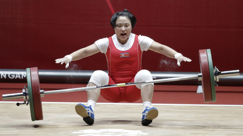North Korean Ri Song Gum falls during her attempt at the women's 48kg weightlifting games at the 18th Asian Games in Jakarta, Indonesia on Monday, Aug. 20, 2018. Ri won gold. (AP Photo/Aaron Favila)