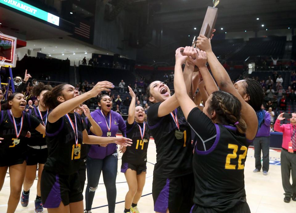 1. Reynoldsburg's Mya Perry (1), Trinity Ramos (22) and Imarianah Russell hoist the Division I state championship trophy after a 63-56 overtime win over Mason on March 12 at the University of Dayton.