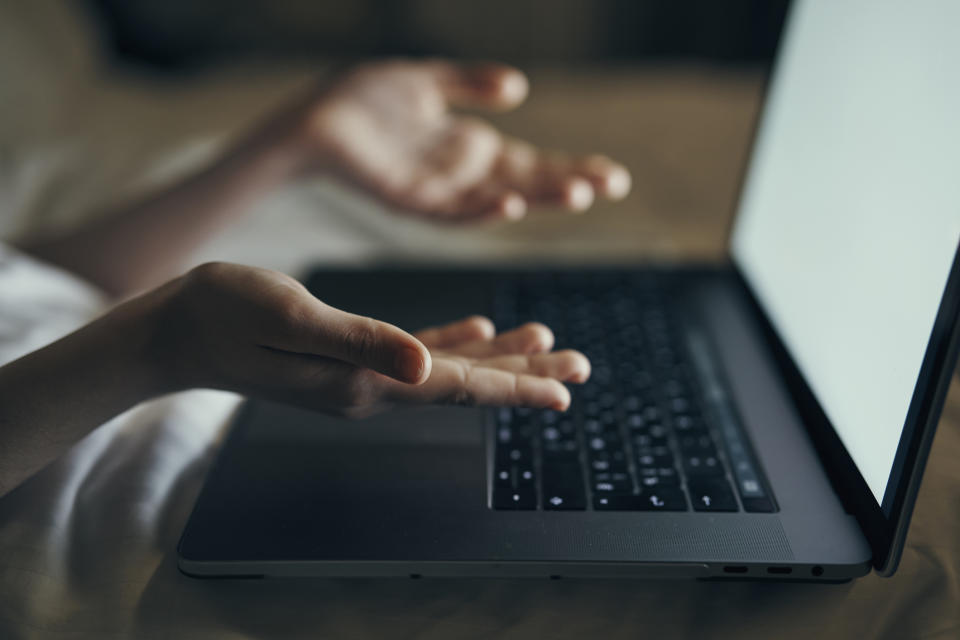 Person gesturing with hands over a laptop keyboard, screen not visible. Context suggests frustration or confusion during computer use