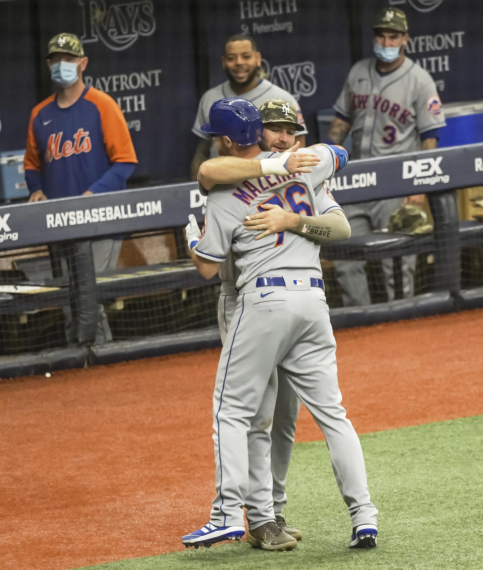 New York Mets' Pete Alonzo hugs Patrick Mazeika (76) outside the dugout after his solo home run off Tampa Bay Rays reliever Diego Castillo during the sixth inning of a baseball game Sunday, May 16, 2021, in St. Petersburg, Fla. (AP Photo/Steve Nesius)