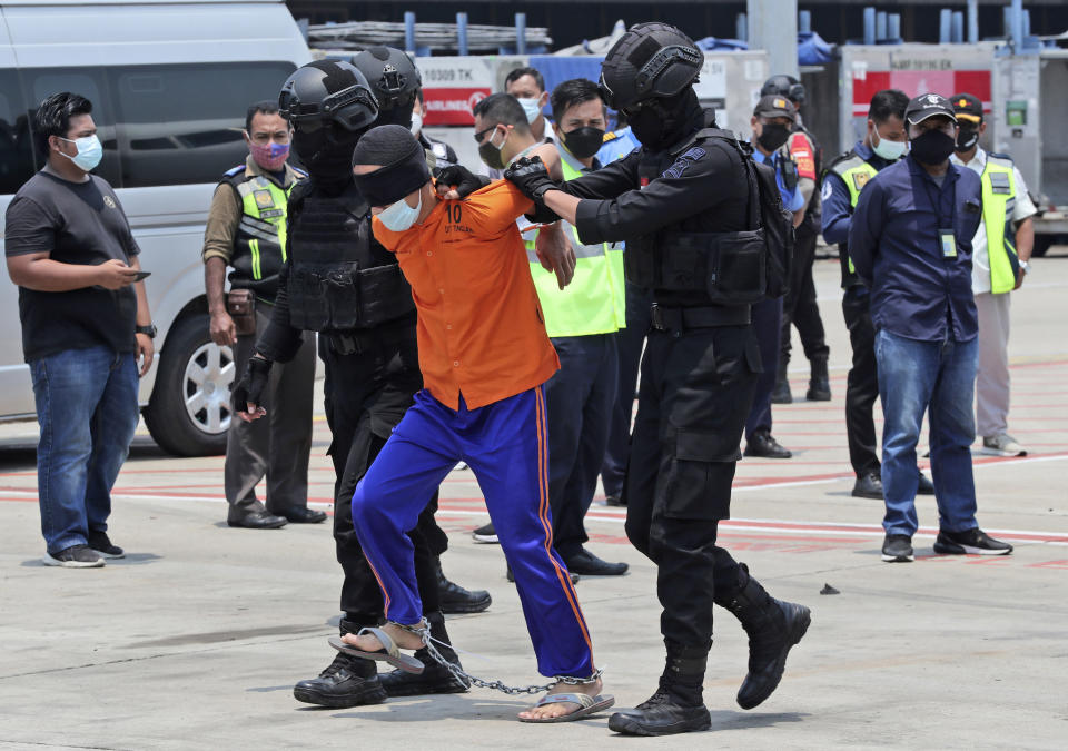 Police escort a suspected militant upon arrival at the Soekarno-Hatta International Airport in Tangerang, Indonesia, Thursday, March 18, 2021. Authorities on Thursday transferred suspected militants arrested in raids in the last few weeks, from East Java to the capital city for further questioning. The militants are believed to be connected to linked to the al-Qaida-linked Jemaah Islamiyah extremist group. (AP Photo/Achmad Ibrahim)