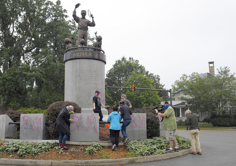 Volunteers, pictured here cleaning spray-paint off the Arthur Ashe memorial.