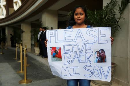 Elsa Ortiz holds a placard with pictures of her son David Tobar, who's currently at a shelter in Houston, Texas, after being separated, while protesting outside the hotel where U.S. Homeland Security Secretary Kirstjen Nielsen is holding a meeting with foreign ministers from Mexico and Central America, in Guatemala City, Guatemala July 10, 2018. REUTERS/Luis Echeverria