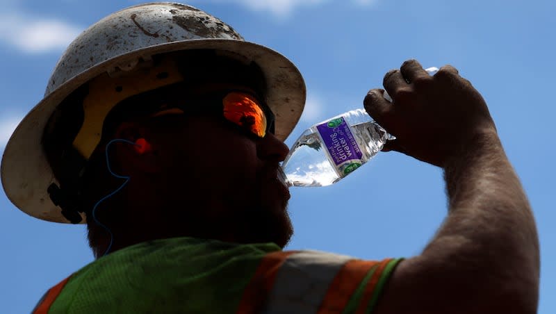 Garrett Rowser hydrates while working on the I-215 Renewed reconstruction project in Salt Lake City on Friday, Aug. 11, 2023.