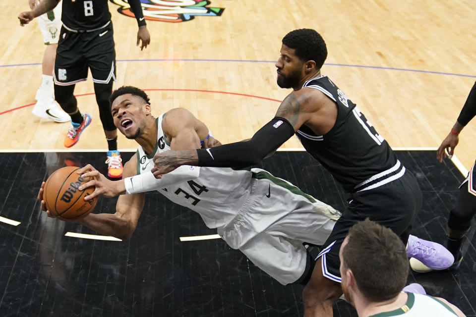 Milwaukee Bucks forward Giannis Antetokounmpo, left, tries to shoots as he falls while under pressure from Los Angeles Clippers forward Paul George during the second half of an NBA basketball game Friday, Feb. 10, 2023, in Los Angeles. (AP Photo/Mark J. Terrill)