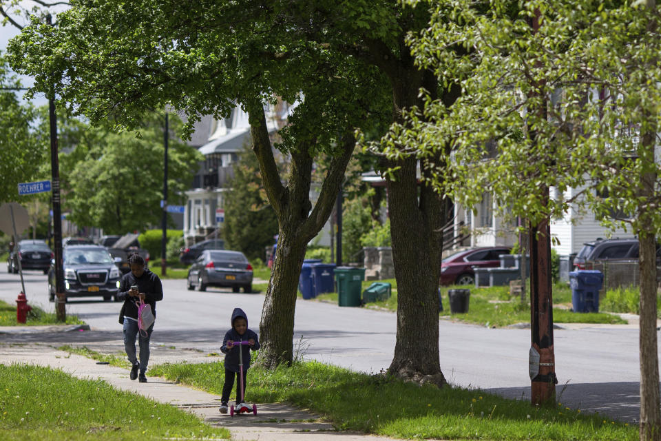 A child scooters along Utica Street near the Tops Friendly Market on Tuesday, May 17, 2022, in Buffalo, N.Y. As the only supermarket for miles, residents say Tops Friendly Market was a sort of community hub where they chatted with neighbors and caught up on each other’s lives. (AP Photo/Joshua Bessex)