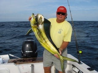 Dick Gruber holding a fish during a fishing trip.