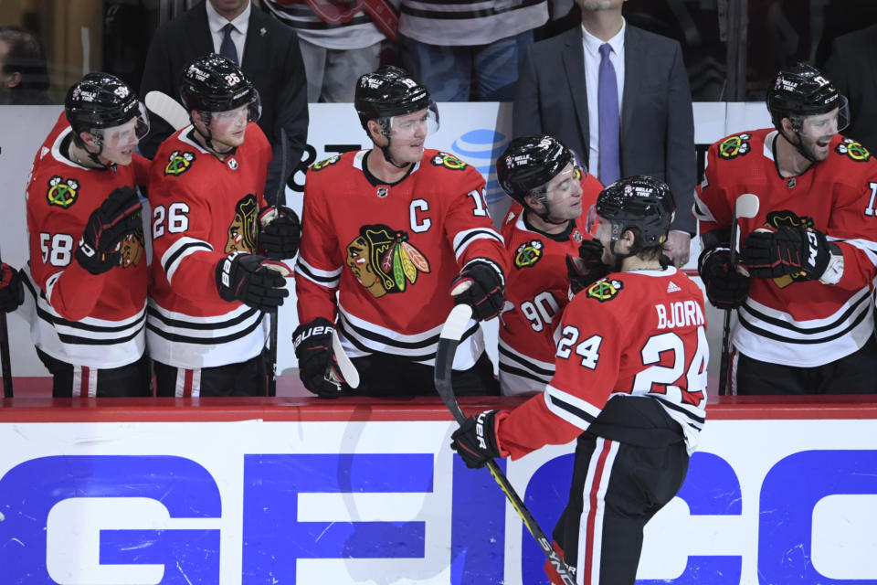 Chicago Blackhawks' Anders Bjork (24) celebrates with teammates at the bench after scoring a goal during the second period of an NHL hockey game against the Minnesota Wild, Monday, April 10, 2023. (AP Photo/Paul Beaty)
