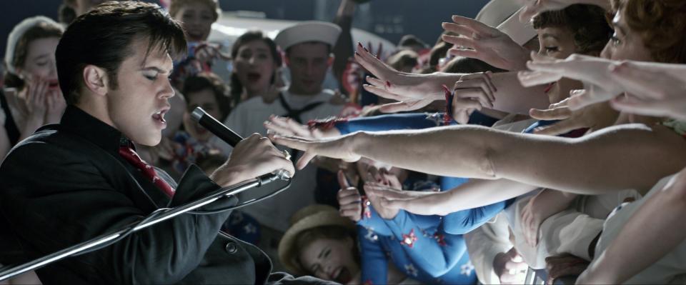 Elvis singing to a crowd of girls reaching for him