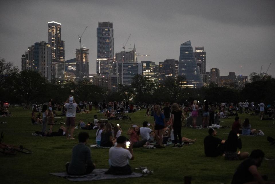 The Austin skyline begins to light up as spectators watch the solar eclipse reach its totality in Zilker Park on Monday, April 8, 2024.