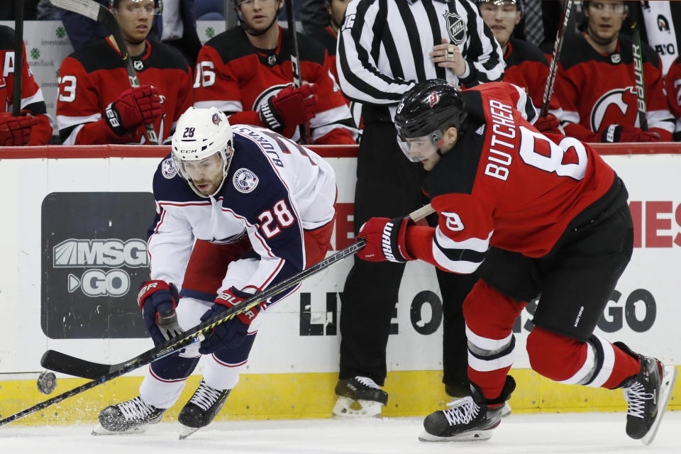 New Jersey Devils defenseman Will Butcher (8) defends against Columbus Blue Jackets right wing Oliver Bjorkstrand (28) during the first period of an NHL hockey game Sunday, Feb. 16, 2020, in Newark, N.J. (AP Photo/Kathy Willens)