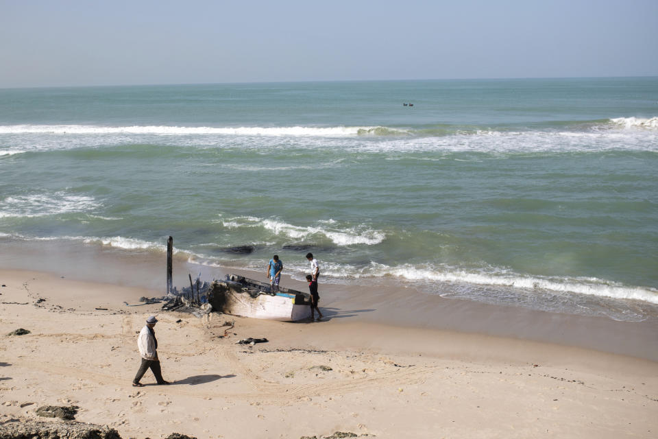 Children play on a fishing boat which smugglers intended to transport migrants, but which was burned by authorities, near La Sarga just outside of Dakhla in Morocco-administered Western Sahara, Tuesday, Dec. 22, 2020. The peninsula city of Dakhla boasts a thriving fishing port, and kitesurfing enthusiasts flock to its waters. But in recent months, its beaches have become a hot spot of the moment for smuggling networks eyeing the Canaries, 500 kilometers (300 miles) north. (AP Photo/Mosa'ab Elshamy)