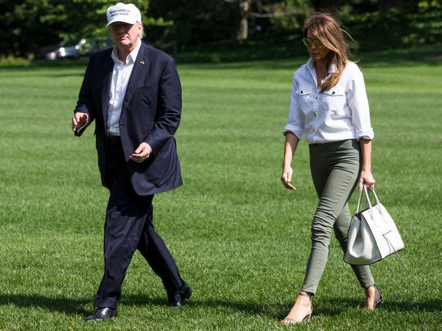 melania trump wearing jeans alongside donald trump walking across the white house lawn in 2017