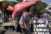A man carries a sack of corn through the Comayaguela market on the outskirts of Tegucigalpa, days after general eletions in Honduras, Tuesday, Nov. 30, 2021. Free Party presidential candidate Xiomara Castro, the wife of ousted former president Manuel Zelaya, has taken a commanding lead in Honduras' elections, capping a 12-year effort. (AP Photo/Moises Castillo)