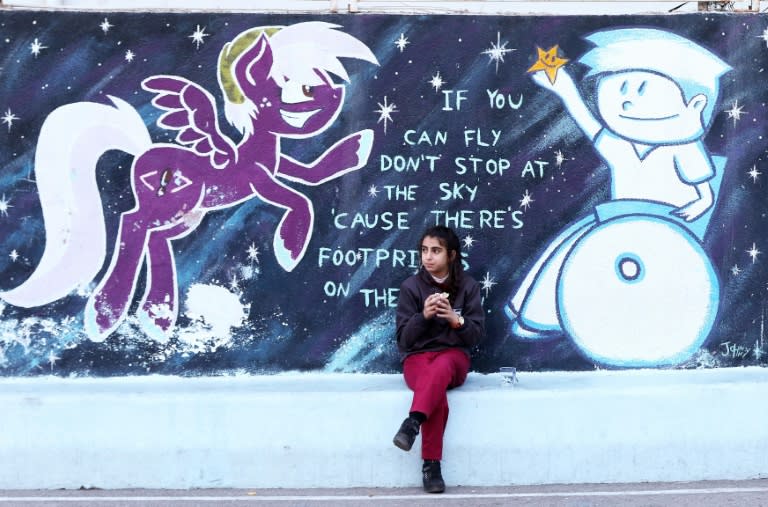 An Iraqi Christian student sits in front of a a mural in a playground at a school in the Jordanian capital Amman