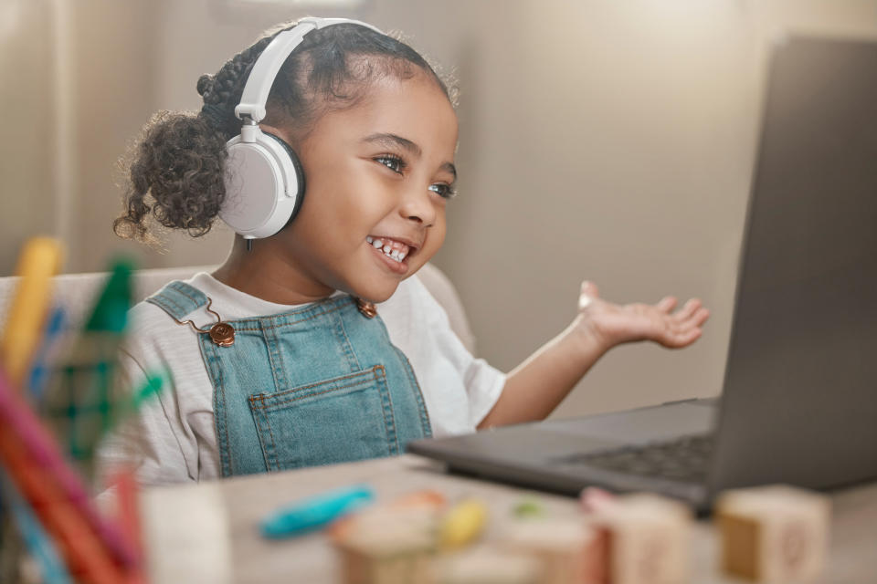 A little girl with headphones doing social distance learning on a laptop