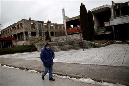 A man walks near destroyed buildings in Gavrilo Princip's hometown Bosansko Grahovo, January 31, 2014. REUTERS/Dado Ruvic