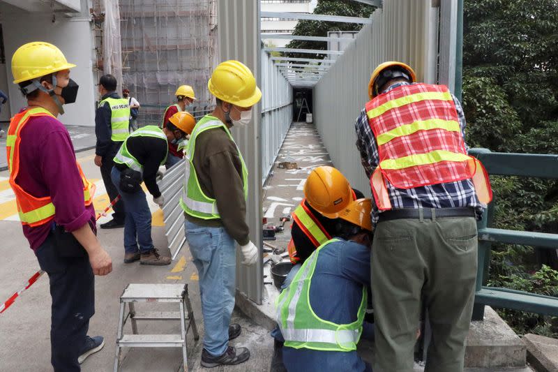 Workers erect construction hoardings around a painted slogan commemorating the 1989 Tiananmen Square crackdown, in Hong Kong