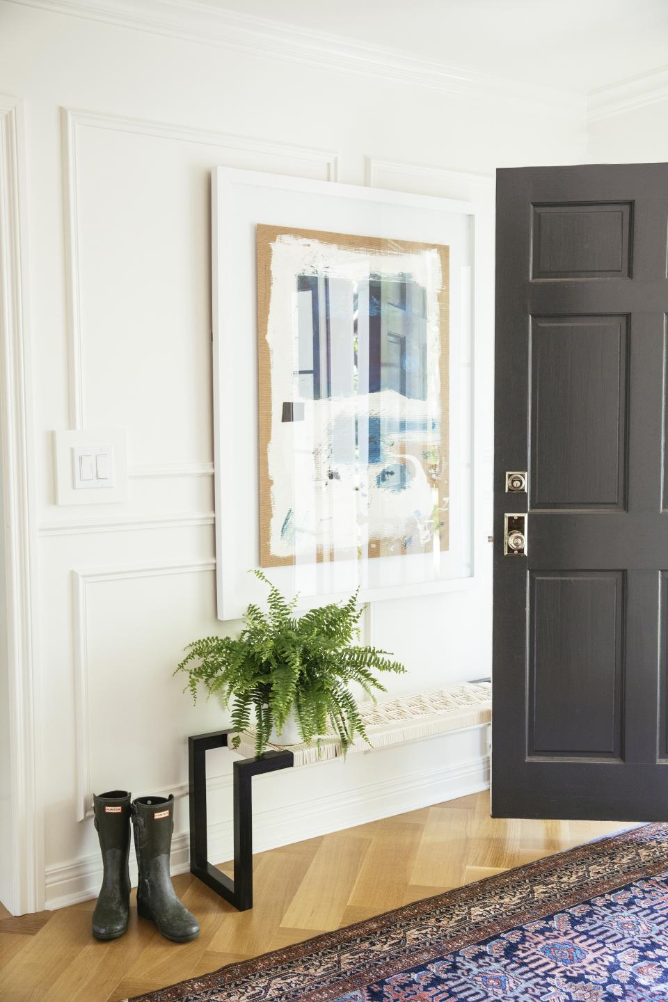 Entryway with wall art, house plant and fall rug.