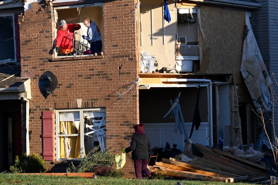Donna Rogers, bottom right, watches while friends toss bags of clothes from the second floor of her son’s damaged home in the West Creek Farms neighborhood on Sunday, Dec. 10, 2023, Clarksville, Tenn. Central Tennessee residents and emergency workers are continuing the cleanup from severe weekend storms. (AP Photo/Mark Zaleski)