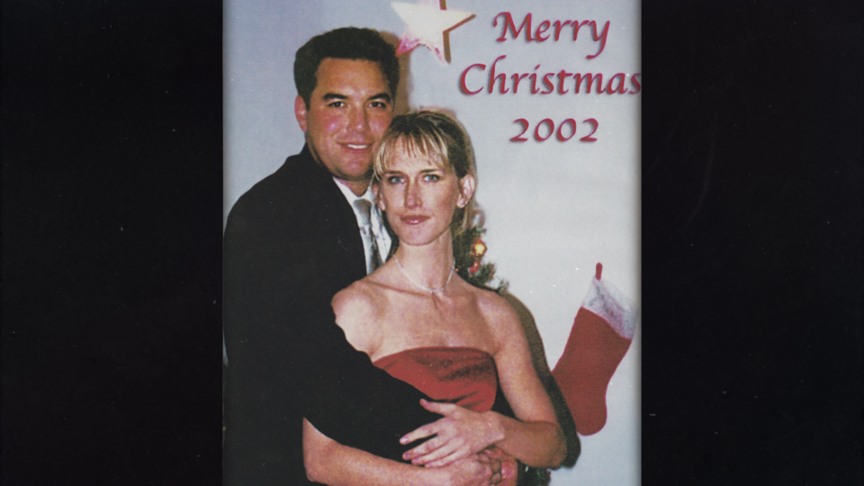 Scott Peterson und Amber Frey umarmen sich vor einem Hintergrund mit der Aufschrift: Frohe Weihnachten 2002.