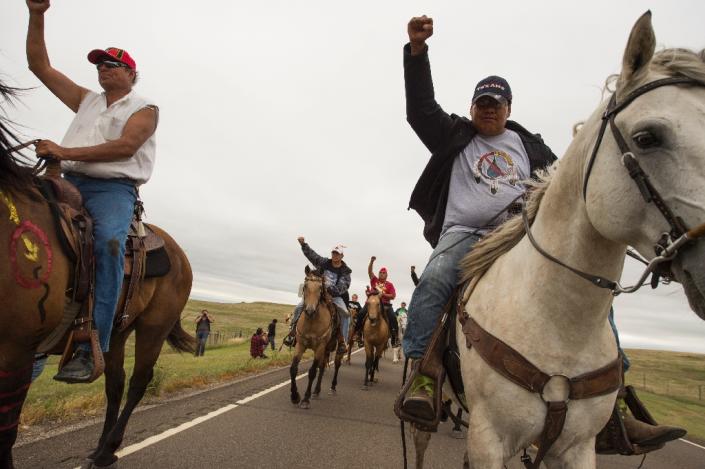 Native Americans ride with raised fists to a sacred burial ground that was disturbed by bulldozers building the Dakota Access Pipeline (AFP Photo/Robyn Beck)