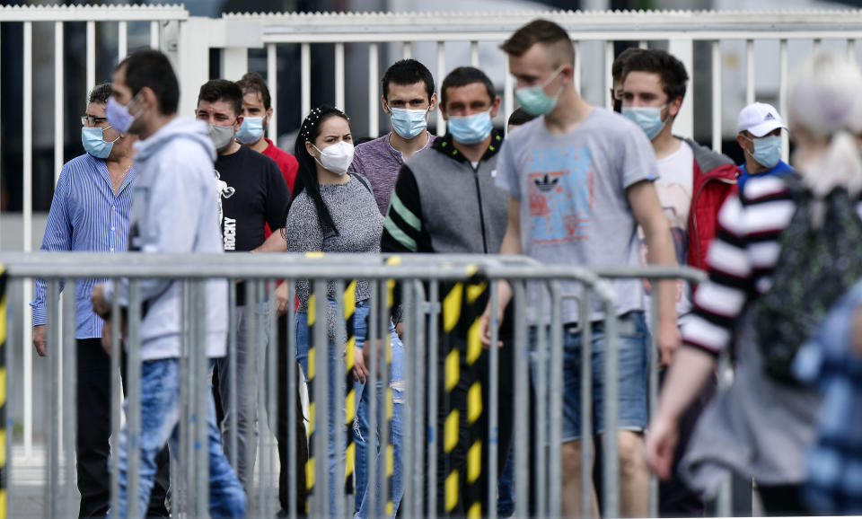 Workers with face masks enter the Toennies meatpacking plant, Europe's biggest slaughterhouse, where the German Bundeswehr army helps to build up a test center for coronavirus in Rheda-Wiedenbrueck, Germany, Friday, June 19, 2020. Hundreds of new COVID-19 cases are linked to a large meatpacking plant, officials ordered the closure of the slaughterhouse, as well as isolation and tests for everyone else who had worked at the Toennies site — putting about 7,000 people under quarantine. (AP Photo/Martin Meissner)