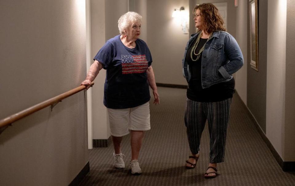 Jeannine Binder, left, and end-of-life doula Ashley Boydston stroll the hallways of Binder’s condo building. Binder’s family asked Boydston to continue to visit her after her husband died in April.