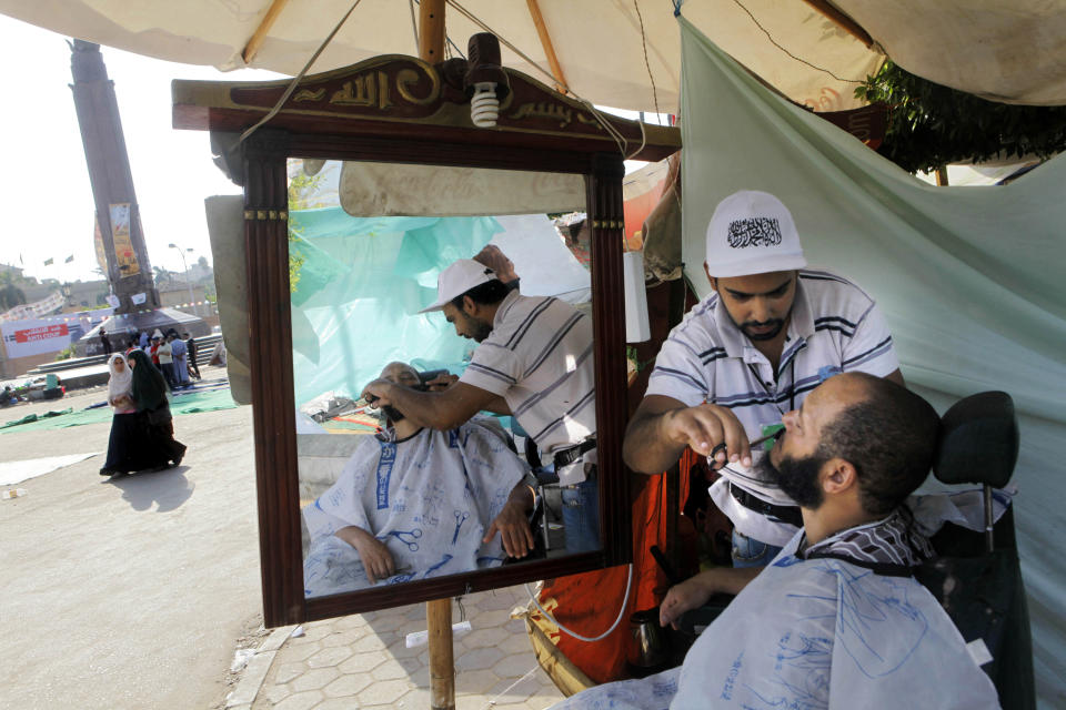 A volunteer barber gorroms a supporter of Egypt's ousted President Mohammed Morsi in a park in front of Cairo University, where protesters have installed their camp in Giza, southwest of Cairo, Egypt, Thursday, Aug. 1, 2013. (AP Photo/Amr Nabil)